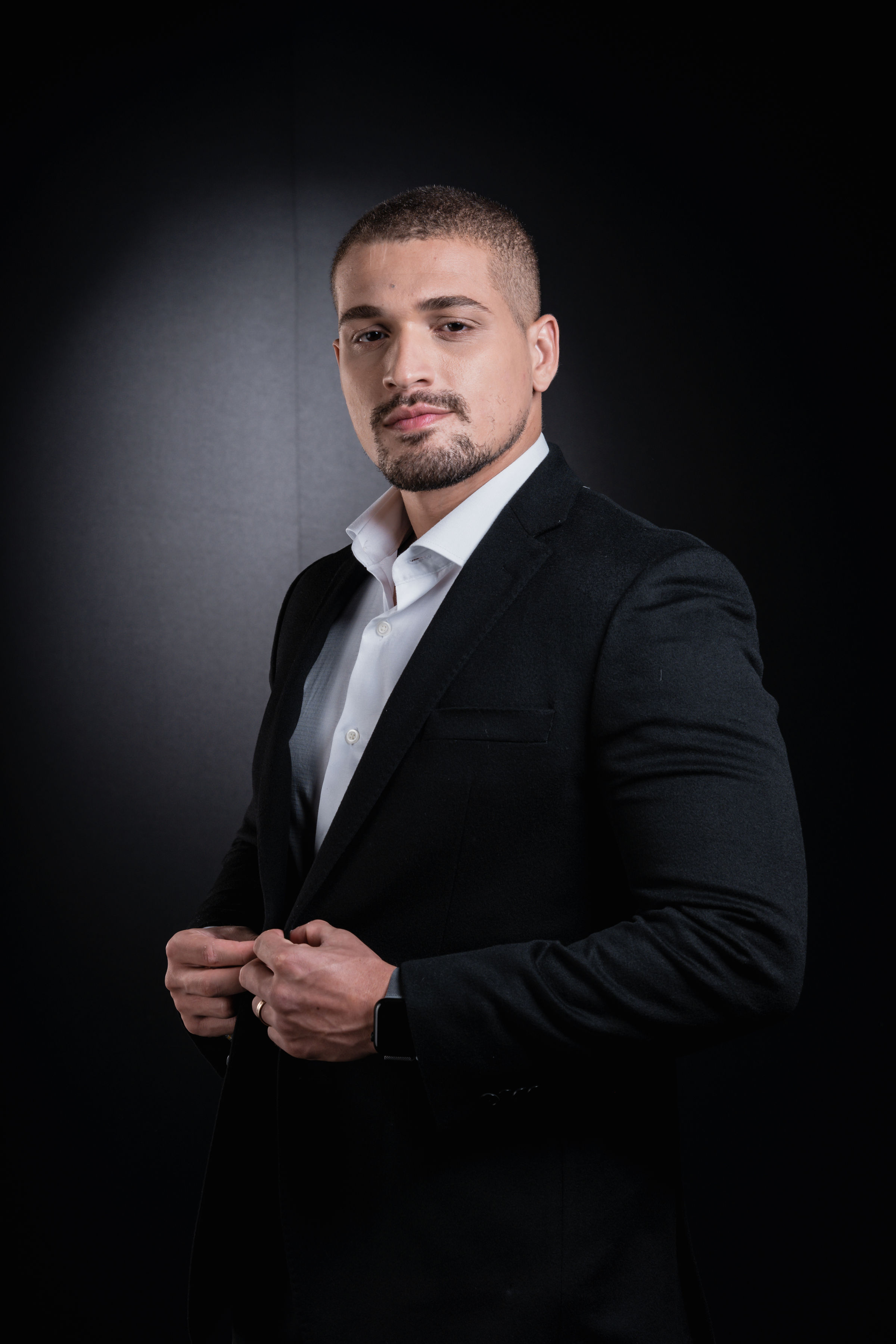 Nicolas Fernandes usando terno preto e camisa branca.